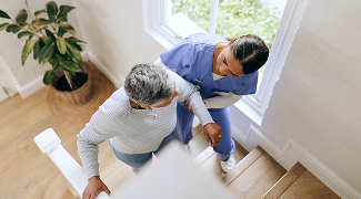 Caregiver assisting an elderly woman while walking up the stairs