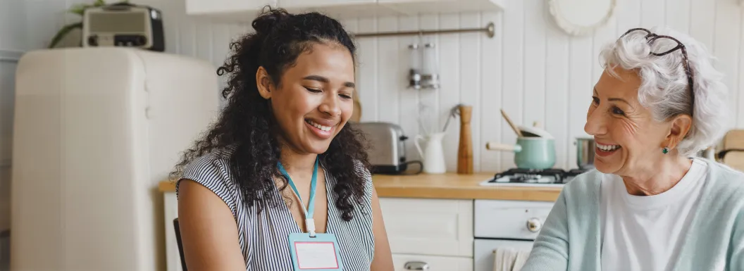 Senior lady having fun building a puzzle at a kitchen table with a caregiver