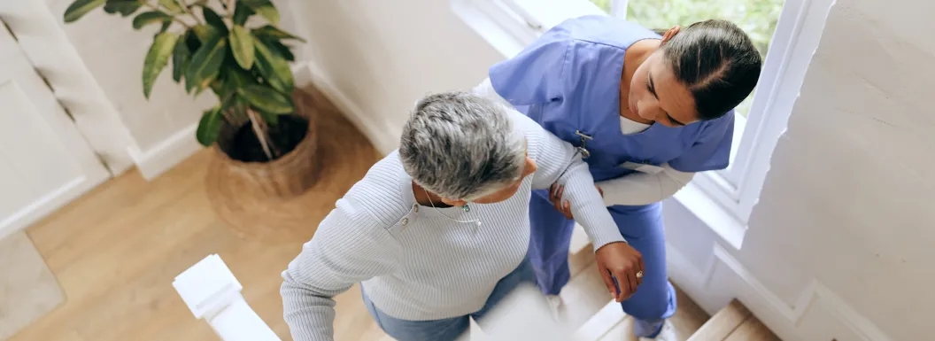 Caregiver assisting an elderly woman while walking up the stairs