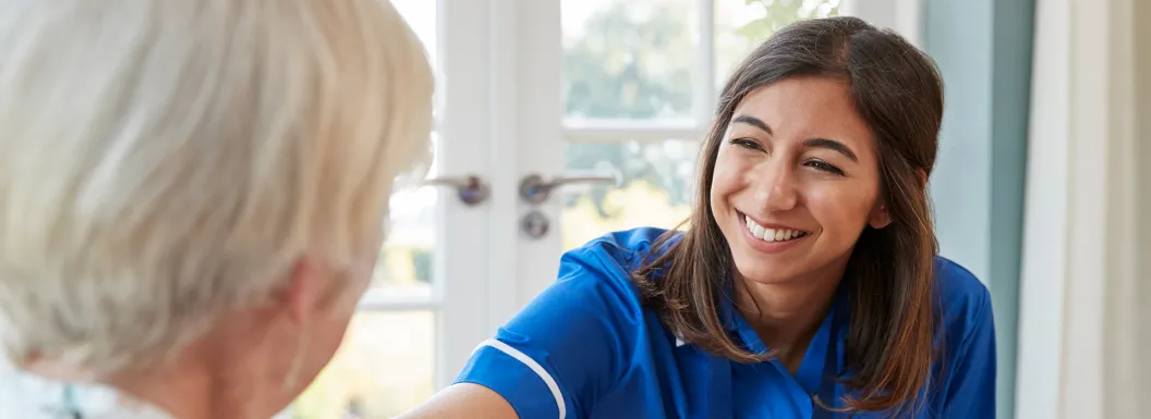 Young care nurse on home visit comforting senior woman