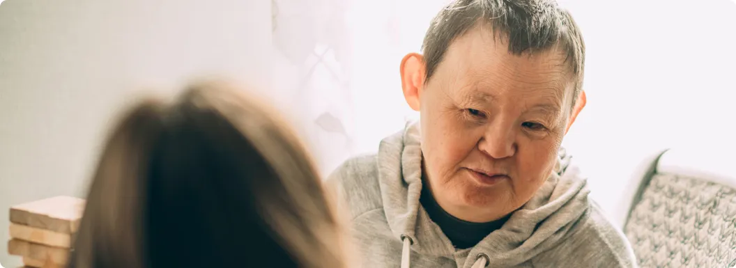 An elderly person with down syndrome talking to a caregiver