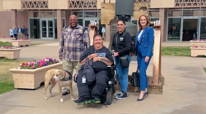 Home Assist Health team members posing for a photo outside with a smiling man in a wheelchair and a service dog