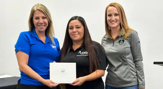 Home Assist Health team members posing for a photo while the woman in the middle is holding a Caregiver of the Year award 