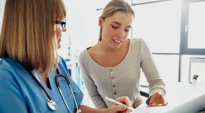Young woman looking at paper with a healthcare professional 