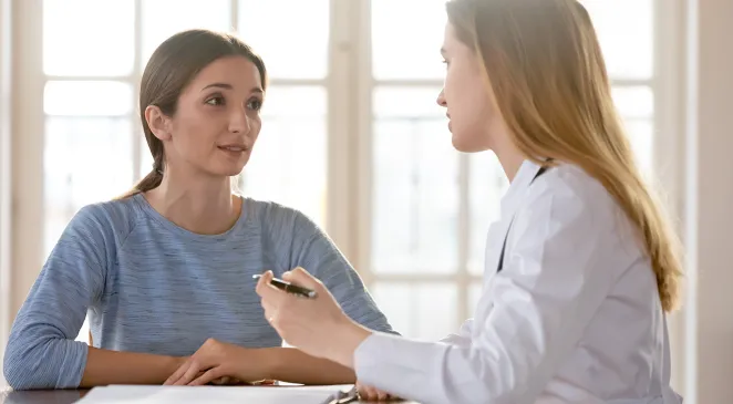 Young woman listening to female general practitioner at meeting 