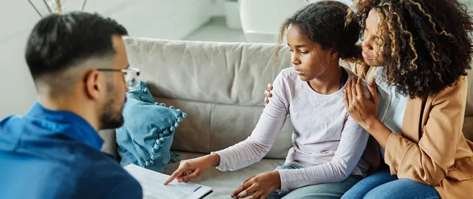 Mother and young doctor talking to a community health workers their home