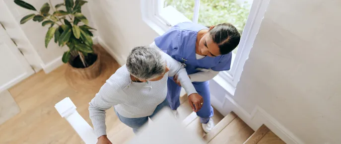 Caregiver assisting an elderly woman while walking up the stairs
