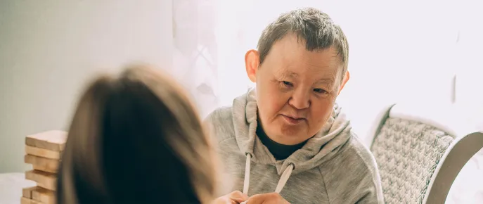 An elderly person with down syndrome talking to a caregiver