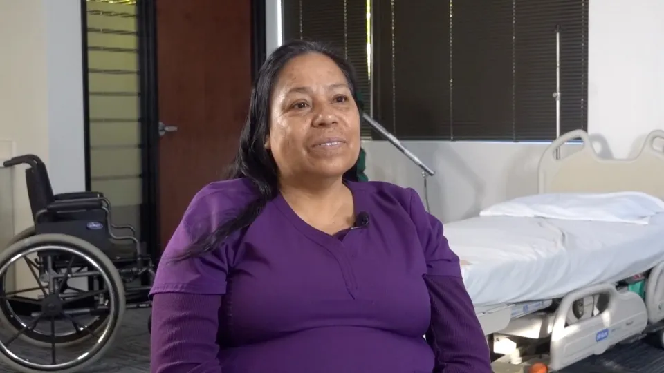 Home Assist Health caregiver wearing purple scrubs, sitting, and talking